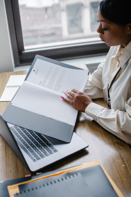 A professional reviewing documents beside a laptop